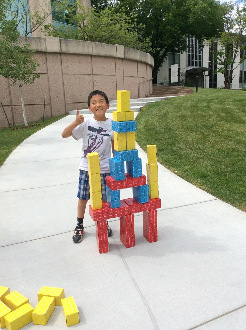 Young man playing with large blocks outdoors in summer camp