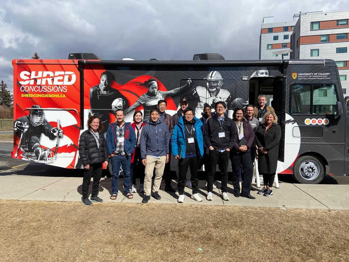 Workshop participants standing in front of a bus that reads, "shred concussions"