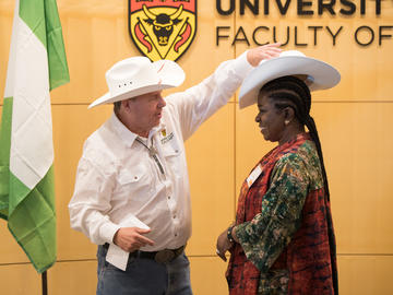 Dean Ian Holloway presents Mrs. Olawunmi Asekun with a white hat for Stampede.