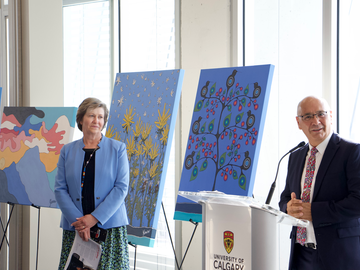 Dean Perrault and Vice Provost Hart stand in front of Dr. Leason's paintings.