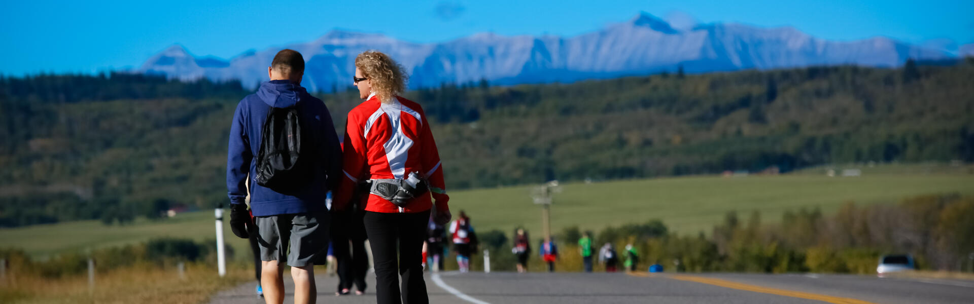 Couple walks along the highway during the 2016 Kidney March with mountains in the background