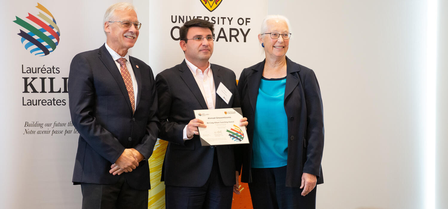 The award recipient holding a certificate with two people.