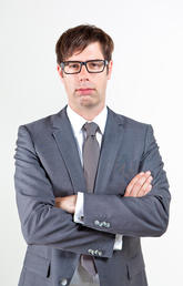 Man with glasses wearing grey suit with arms crossed