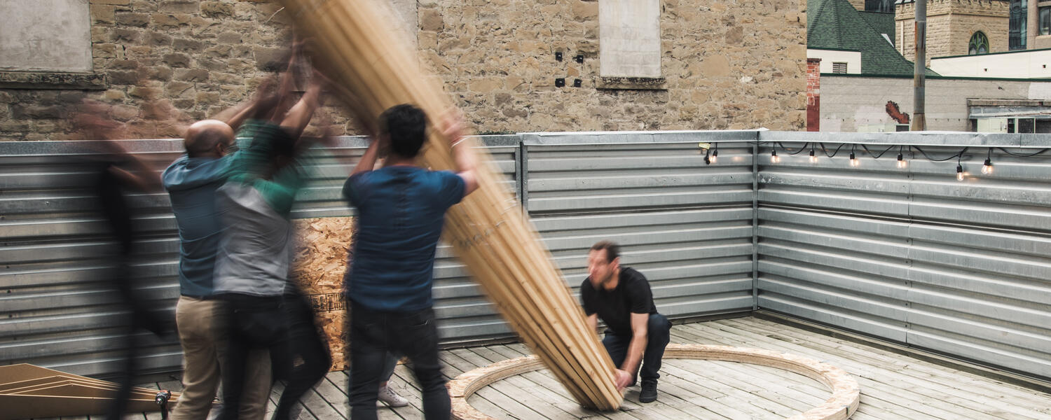men holding a wood pole