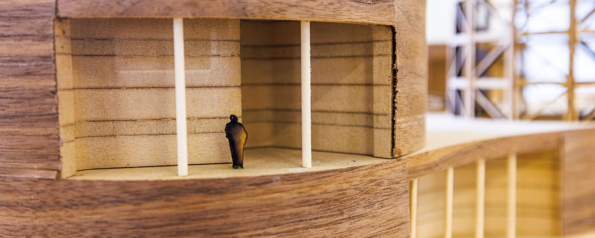 A wooden building model with a human figure standing inside.