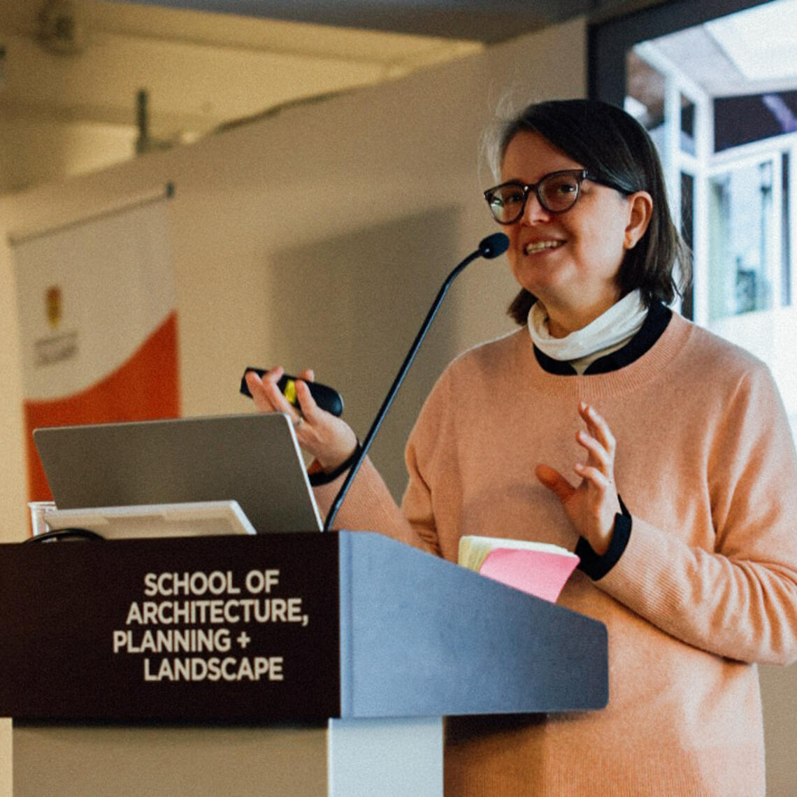 Hilary Sample speaking at a podium in the CBDL building.