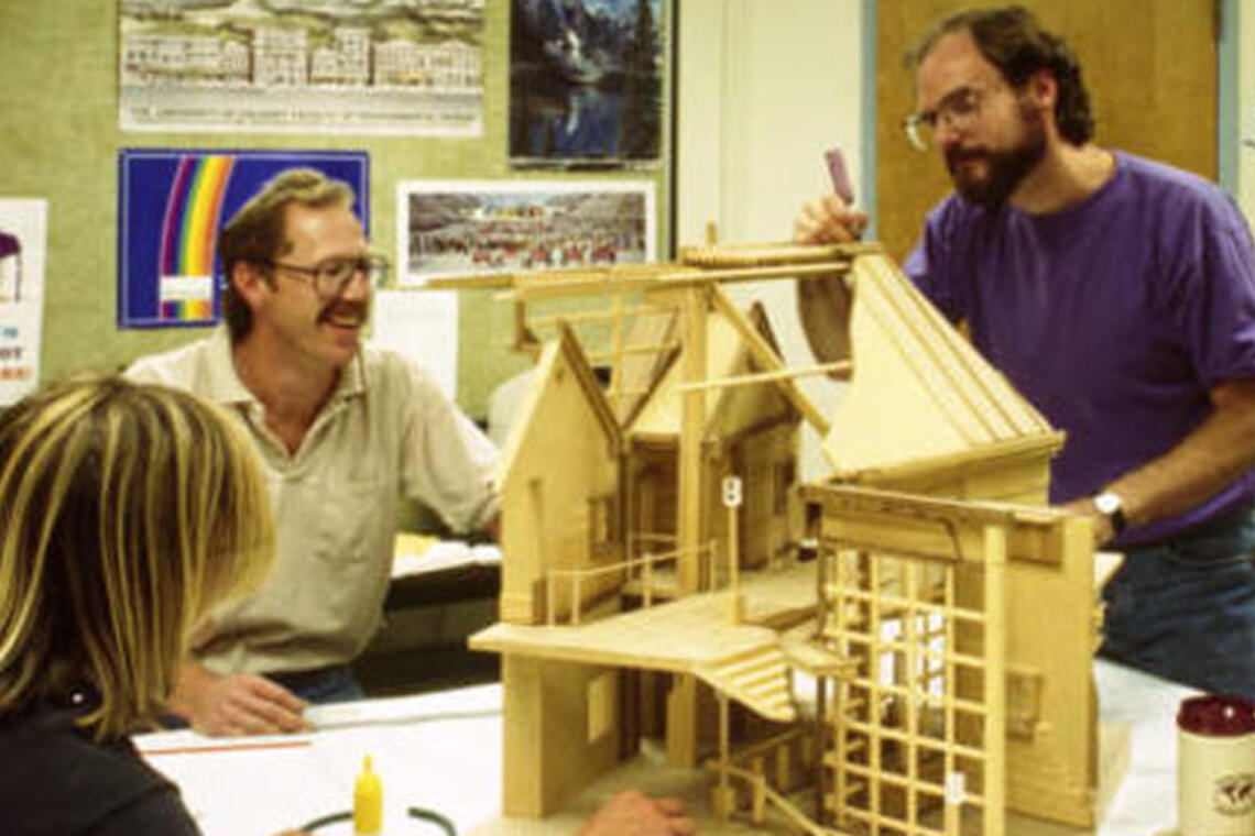 Two instructors help students build an architectural model.