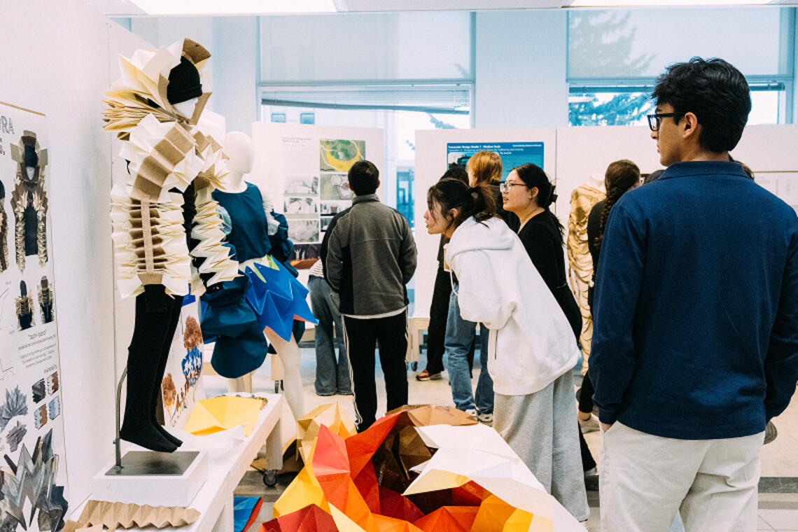 A group of people examine SAPL student work in large gallery space.