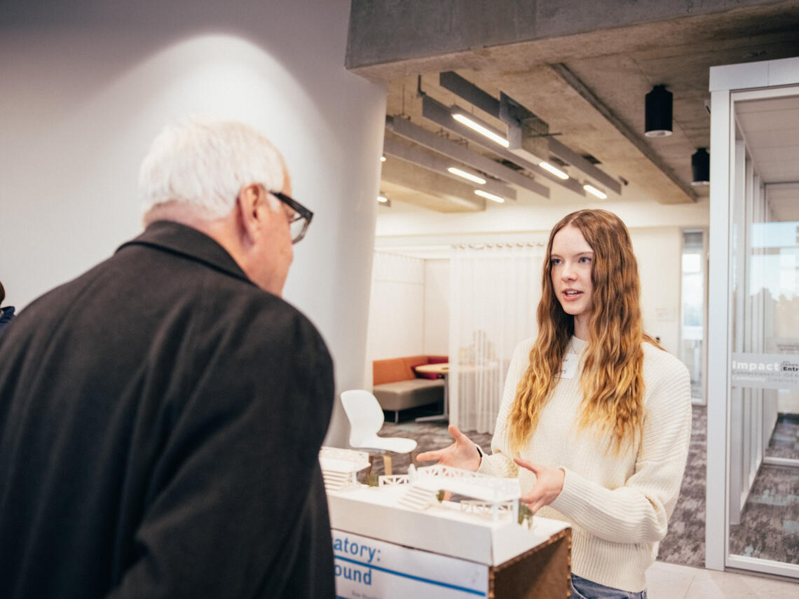 A student presenting a building diorama to a member of the public.