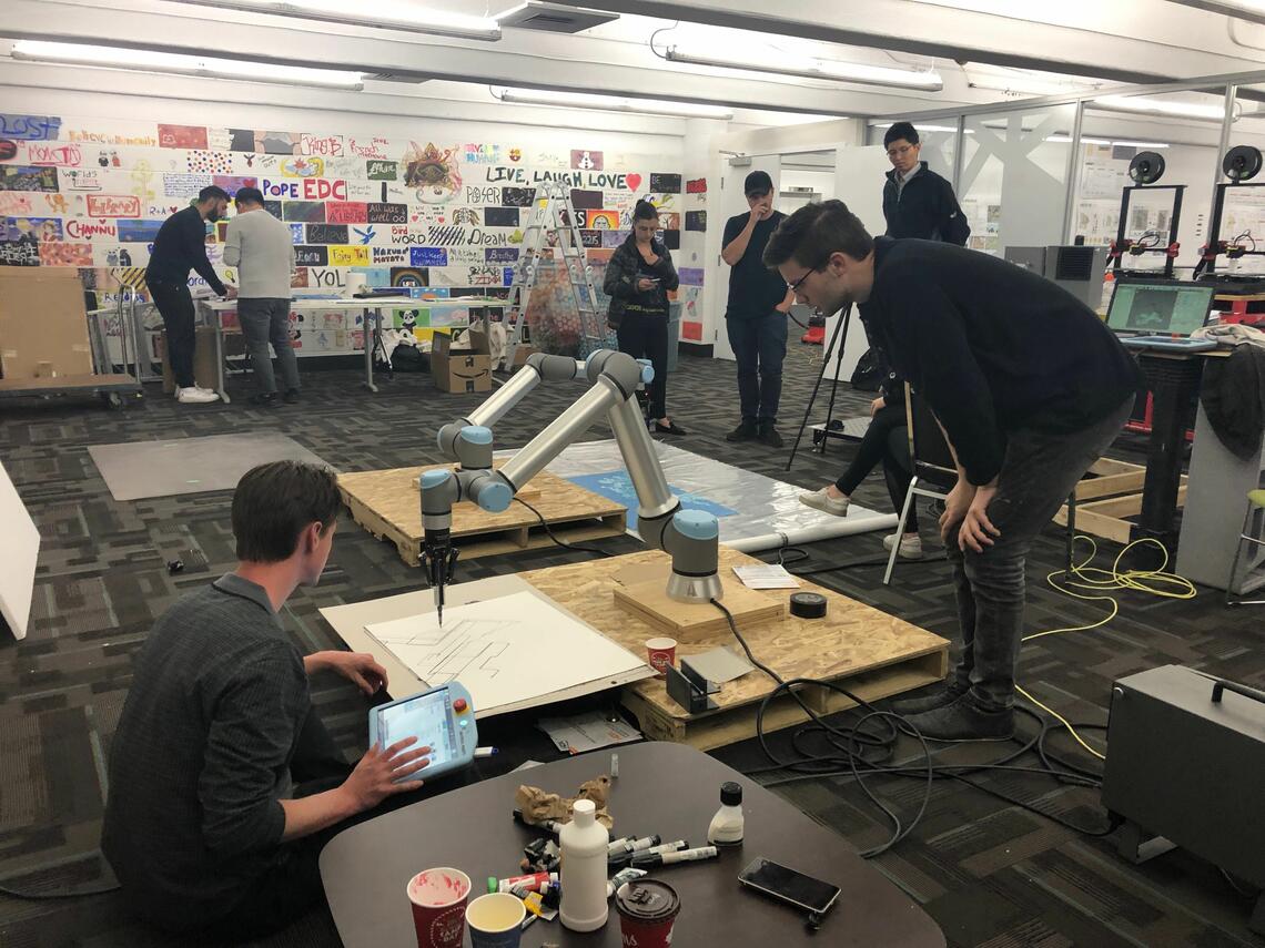 Students creating a design drawing with the support of a robot