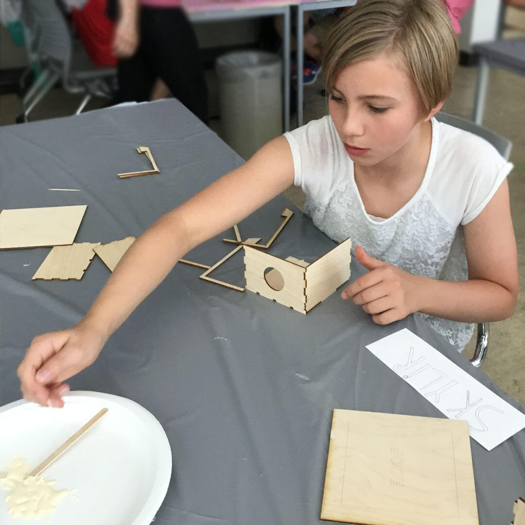 Student at Design Camp builds a bird house with wood